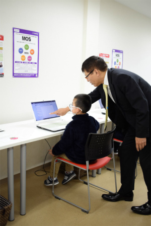 講師が子どもの隣でパソコン操作を直接指導している様子
